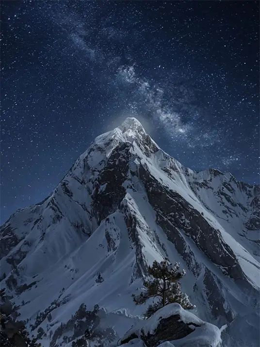 Covered mountain peak under starry sky